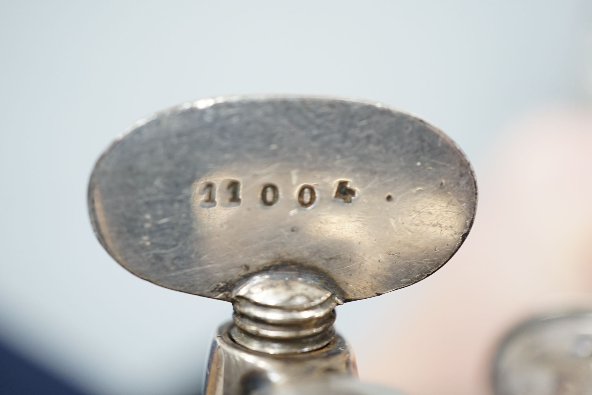 A silver mounted rattle, a white metal mounted double ended ruby glass cent bottle and a silver plated handled roast joint holder.